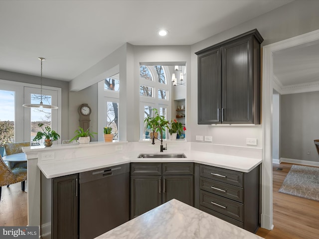 kitchen with dishwasher, light countertops, a peninsula, light wood-style floors, and a sink