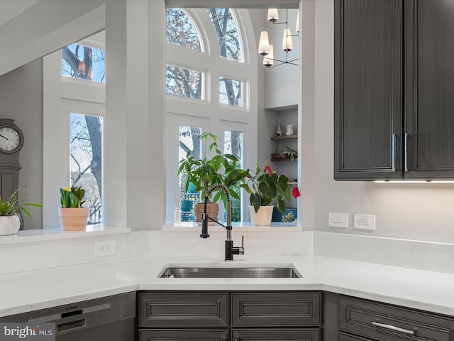 kitchen with dishwasher, light countertops, a chandelier, and a sink