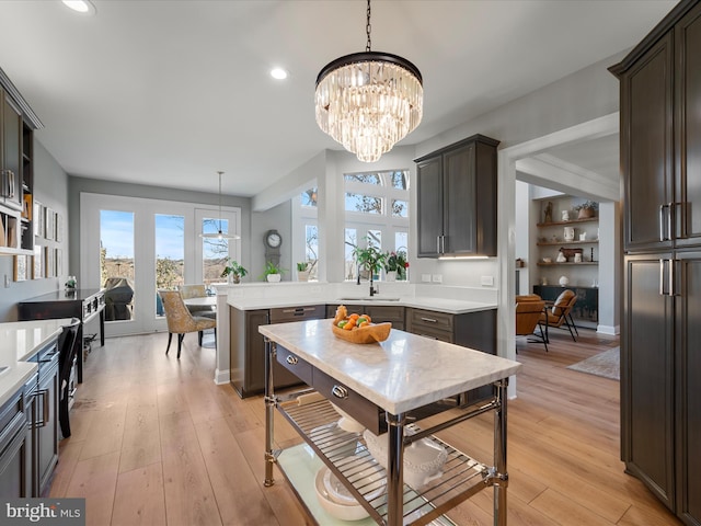 kitchen featuring a peninsula, light countertops, light wood-type flooring, and dark brown cabinetry