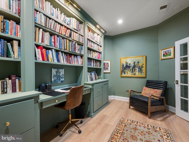 office with built in features, baseboards, visible vents, light wood-style flooring, and crown molding