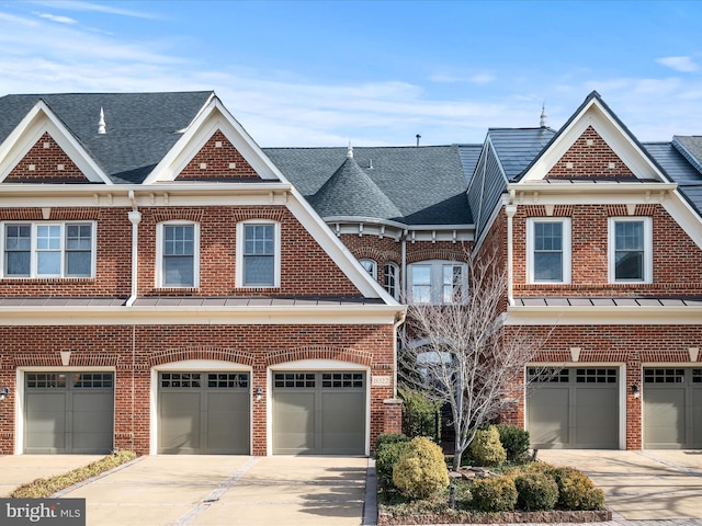 townhome / multi-family property with driveway, a standing seam roof, roof with shingles, an attached garage, and brick siding