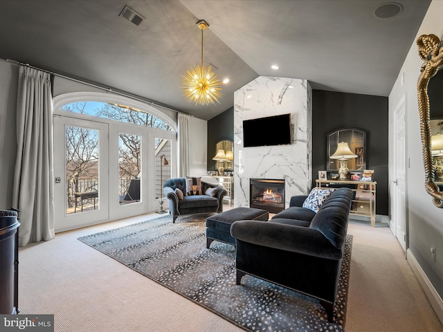 carpeted living room featuring visible vents, lofted ceiling, a high end fireplace, french doors, and a notable chandelier