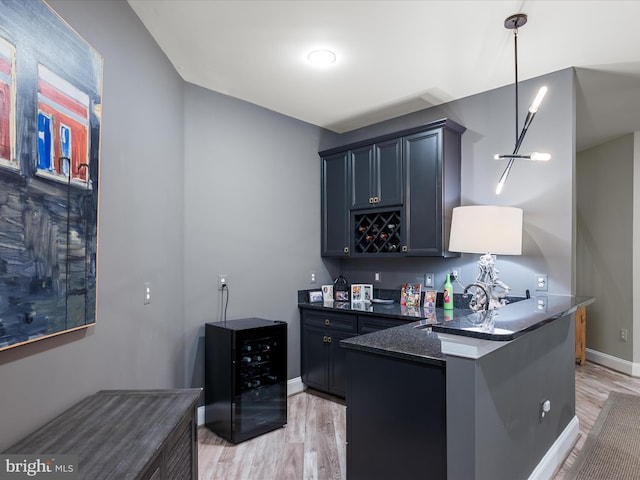 kitchen with wine cooler, light wood-style flooring, a peninsula, and a sink