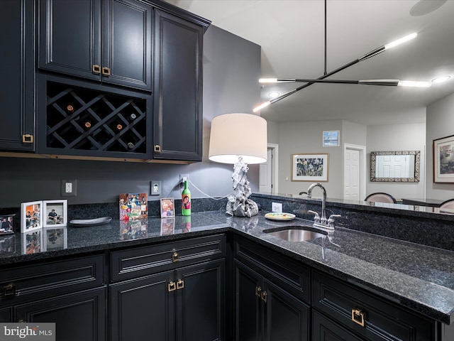 kitchen with a sink, dark cabinets, and dark stone countertops