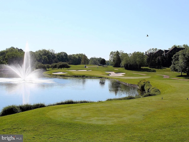 view of community featuring a yard, a water view, and view of golf course