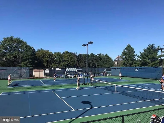 view of tennis court featuring community basketball court and fence