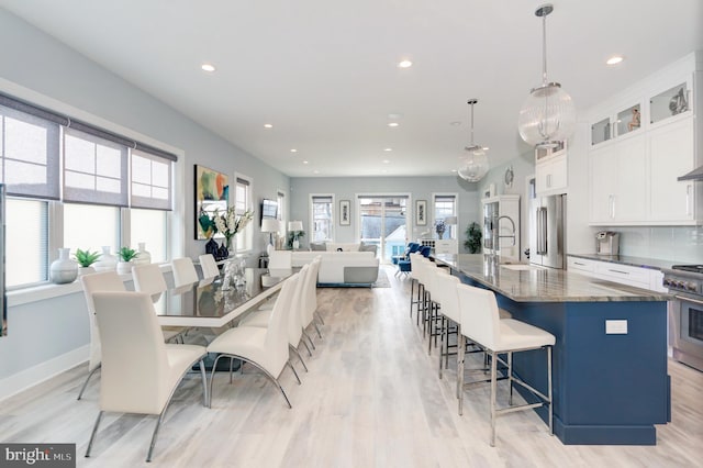 kitchen with pendant lighting, white cabinetry, a kitchen bar, a large island with sink, and high end appliances