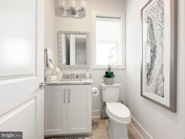 bathroom with hardwood / wood-style flooring, vanity, and toilet