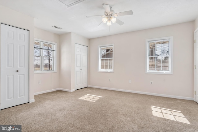 unfurnished bedroom featuring multiple closets and light colored carpet