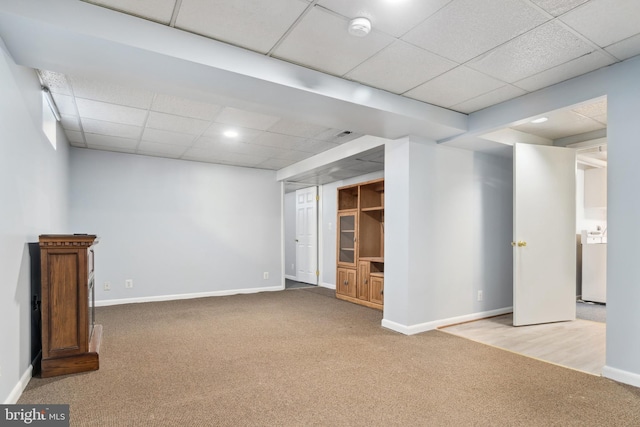 basement featuring a drop ceiling and light colored carpet