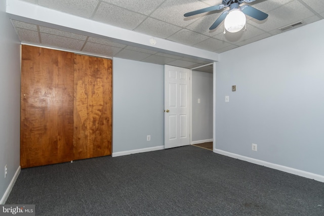 spare room featuring dark colored carpet, a paneled ceiling, and ceiling fan