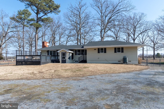 single story home with a wooden deck, central AC, and a front yard