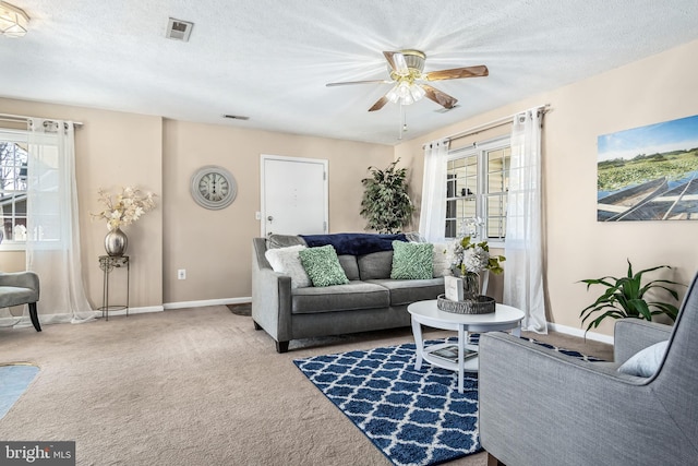 carpeted living room featuring ceiling fan and a textured ceiling