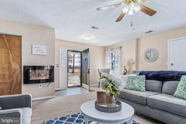 living room featuring ceiling fan, light colored carpet, and a textured ceiling