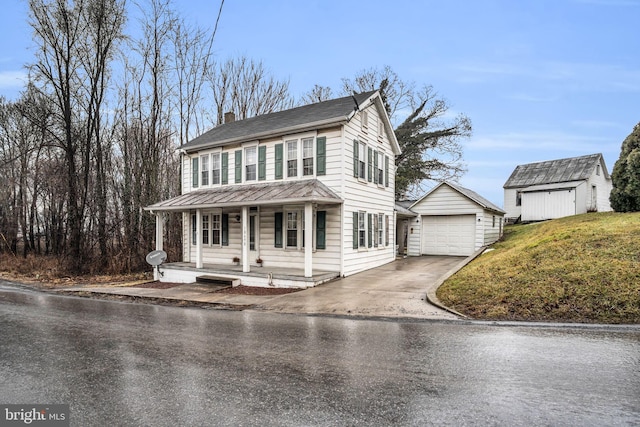 view of front of house with a garage, an outbuilding, a front lawn, and covered porch