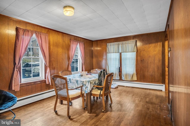 dining room with a baseboard radiator, hardwood / wood-style floors, and wood walls