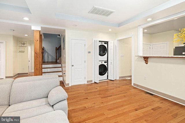 1034 Excelsior Dr, Upper Chichester, PA 19014 - living room with stacked washing maching and dryer, a raised ceiling, and light hardwood / wood-style flooring