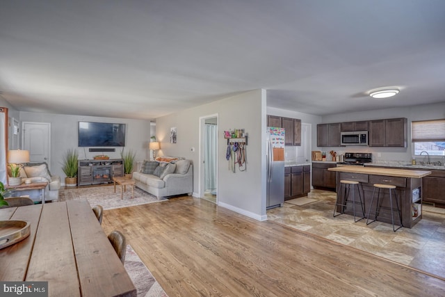 kitchen featuring sink, a breakfast bar area, stainless steel appliances, dark brown cabinetry, and a kitchen island