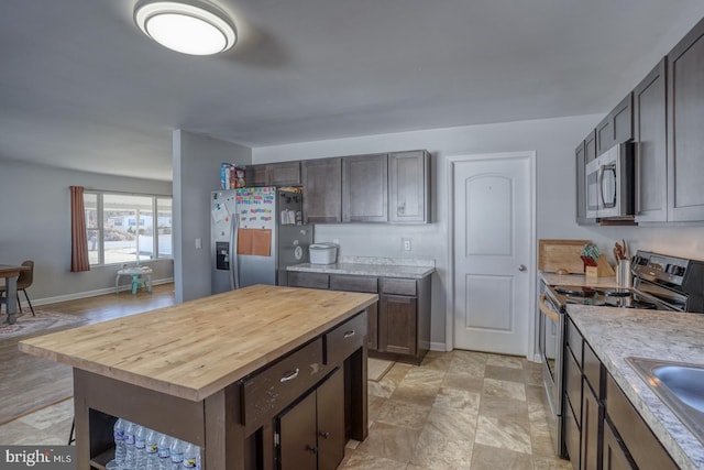 kitchen featuring stainless steel appliances, sink, wooden counters, and dark brown cabinets