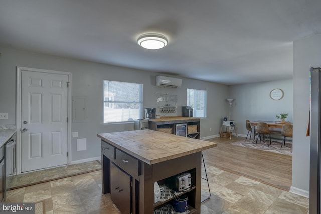 kitchen featuring wood counters, a wall mounted air conditioner, a wealth of natural light, and a center island