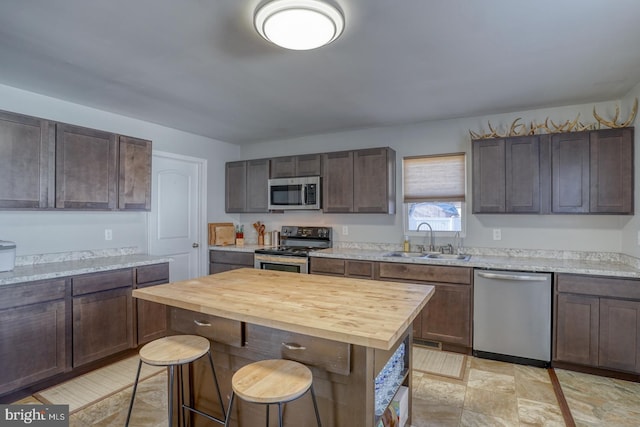 kitchen featuring stainless steel appliances, dark brown cabinets, sink, and wood counters