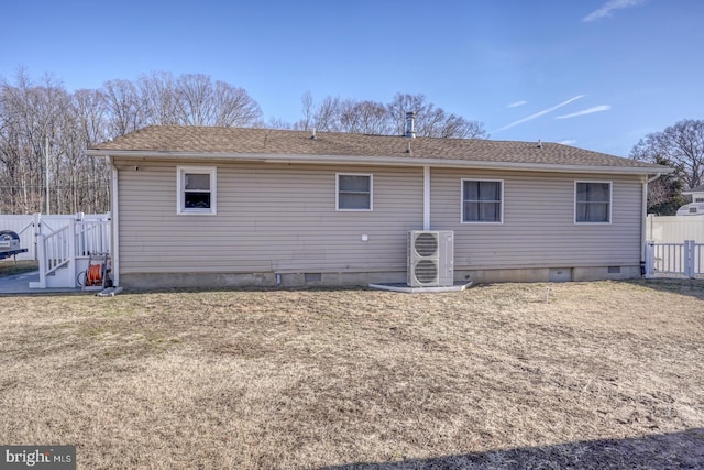 rear view of property with ac unit and a lawn