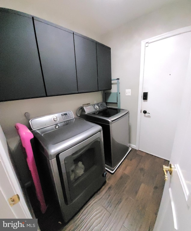 clothes washing area with cabinets, dark hardwood / wood-style floors, and independent washer and dryer