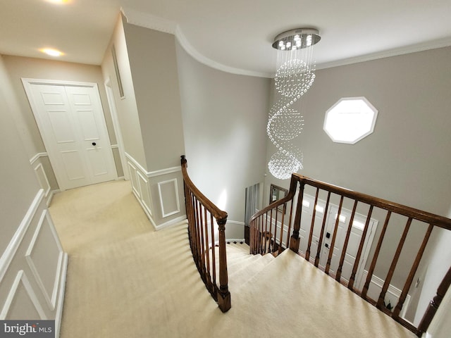 staircase with carpet flooring, a notable chandelier, and ornamental molding