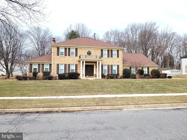 colonial house featuring a front lawn and a balcony