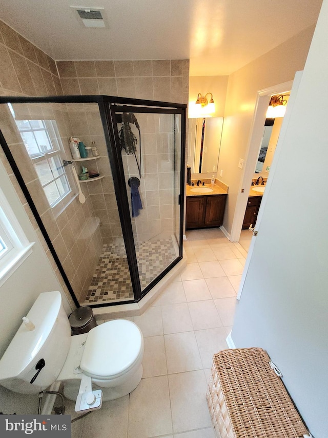 bathroom featuring tile patterned floors, toilet, vanity, and walk in shower