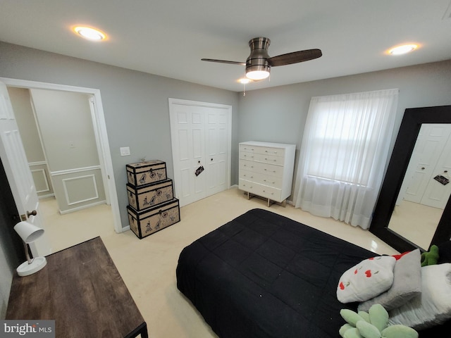 bedroom featuring a closet, light colored carpet, and ceiling fan