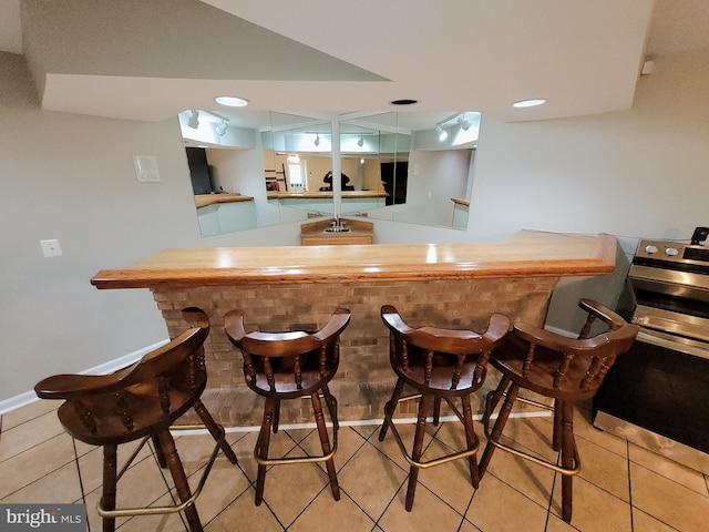 bar with stainless steel electric range and light tile patterned flooring