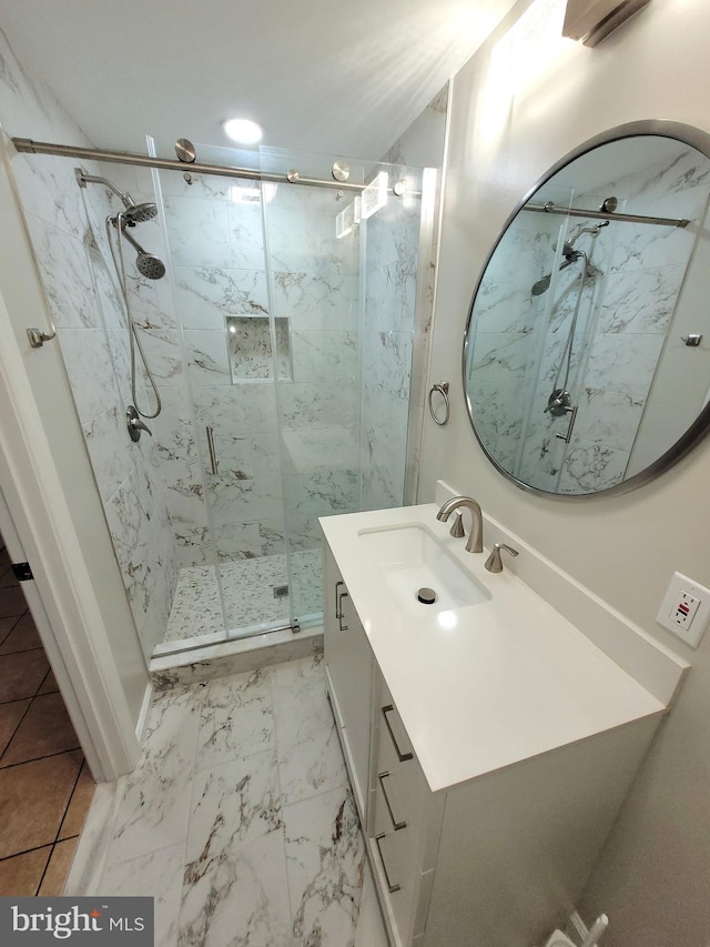 bathroom featuring a shower with shower door and vanity