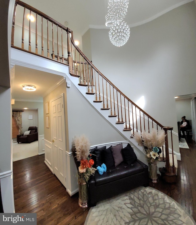 stairway with hardwood / wood-style flooring, crown molding, and a chandelier