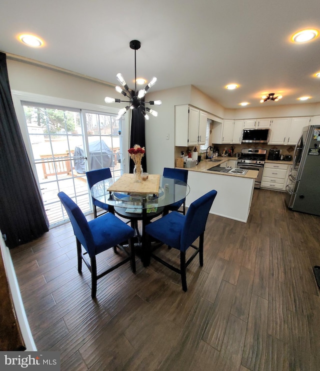 dining space with sink, a chandelier, and dark wood-type flooring