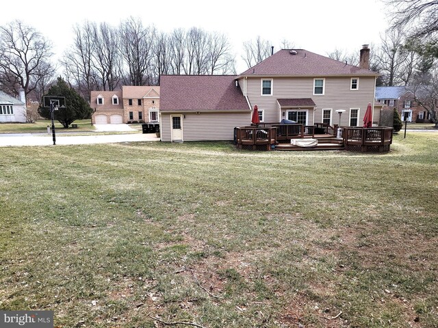 back of house featuring a yard, a wooden deck, and a garage