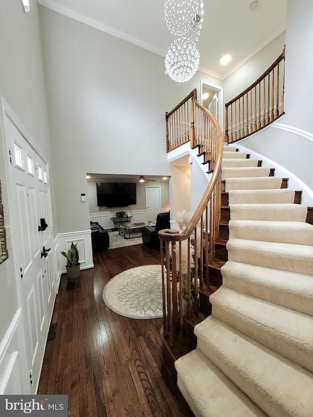 foyer featuring ornamental molding, dark wood-type flooring, a high ceiling, and an inviting chandelier