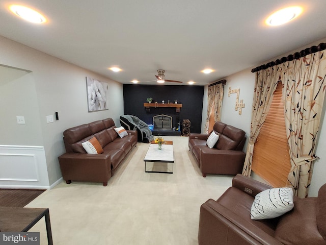 living room featuring a brick fireplace, carpet flooring, and ceiling fan