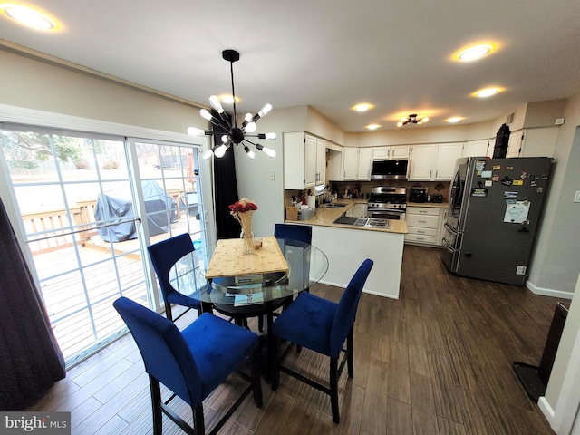 dining room featuring an inviting chandelier, sink, and dark wood-type flooring