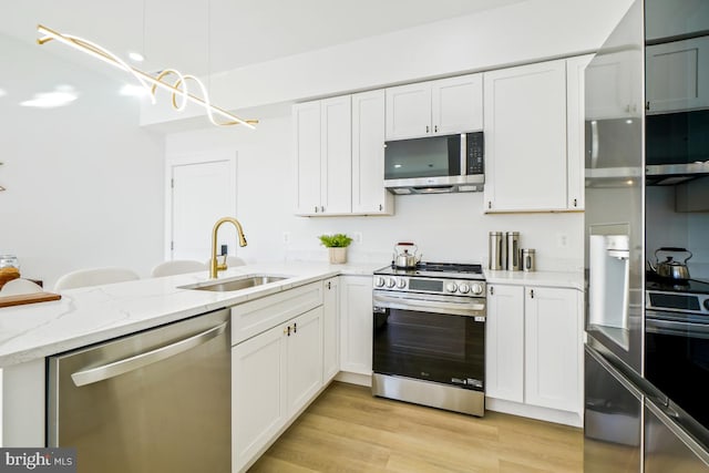 kitchen featuring white cabinetry, sink, stainless steel appliances, light stone countertops, and light wood-type flooring