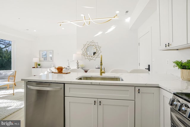 kitchen with light stone counters, sink, white cabinets, and appliances with stainless steel finishes