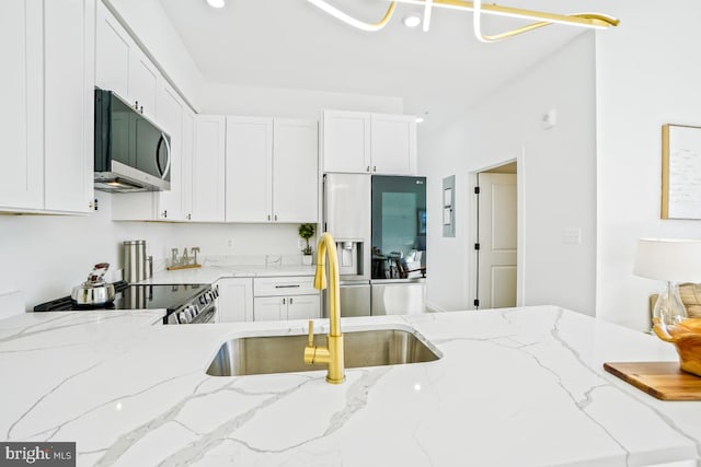 kitchen featuring stainless steel appliances, light stone countertops, sink, and white cabinets