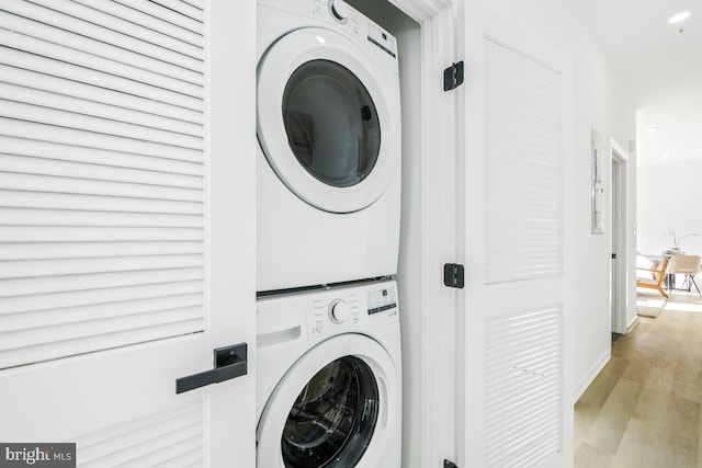 laundry area with stacked washer and clothes dryer and light wood-type flooring