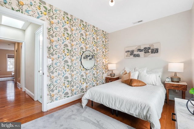 bedroom with hardwood / wood-style flooring and a skylight