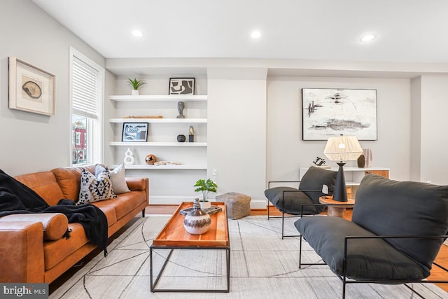 living room featuring built in features and light hardwood / wood-style flooring