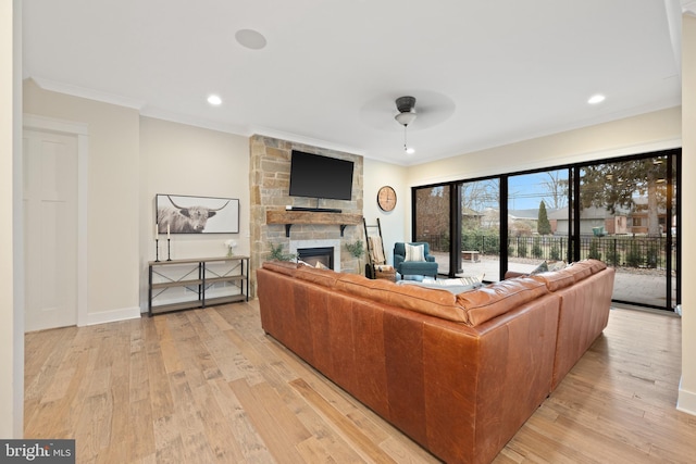 living room with crown molding, a stone fireplace, light hardwood / wood-style floors, and ceiling fan