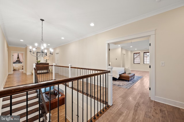 hallway with hardwood / wood-style flooring, crown molding, and an inviting chandelier