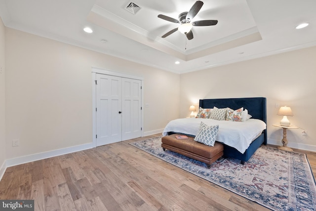 bedroom featuring a raised ceiling, crown molding, hardwood / wood-style floors, and ceiling fan