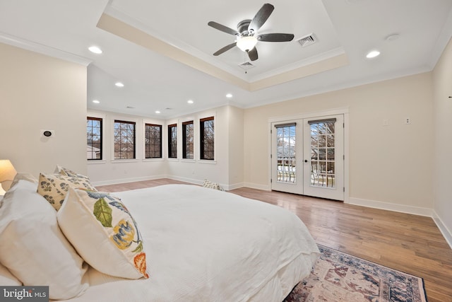 bedroom featuring a raised ceiling, crown molding, access to outside, and french doors