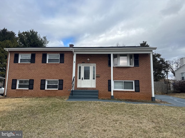 bi-level home featuring entry steps, brick siding, and a front yard